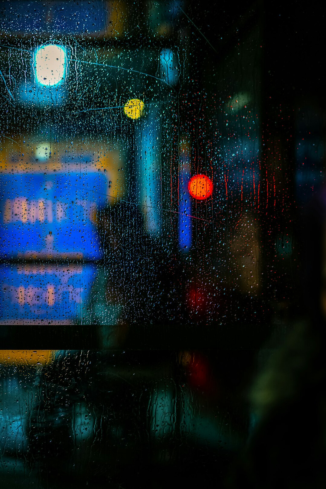Rainy window with blurred city lights at night